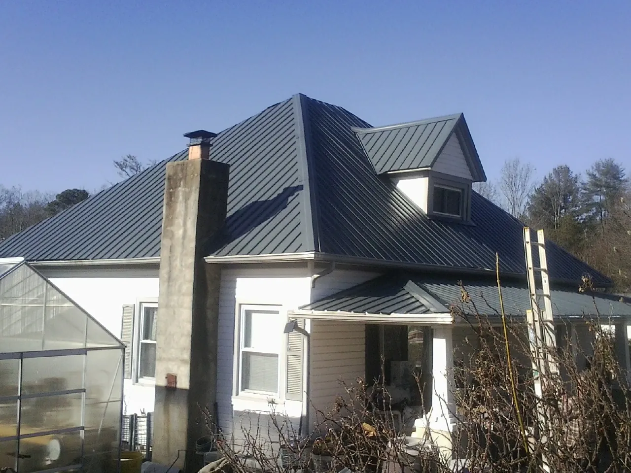 Dark blue standing seam metal roof on a white farmhouse with dormer — Slate & Tile Roof Repair by Roofing Brothers in Minnesota City