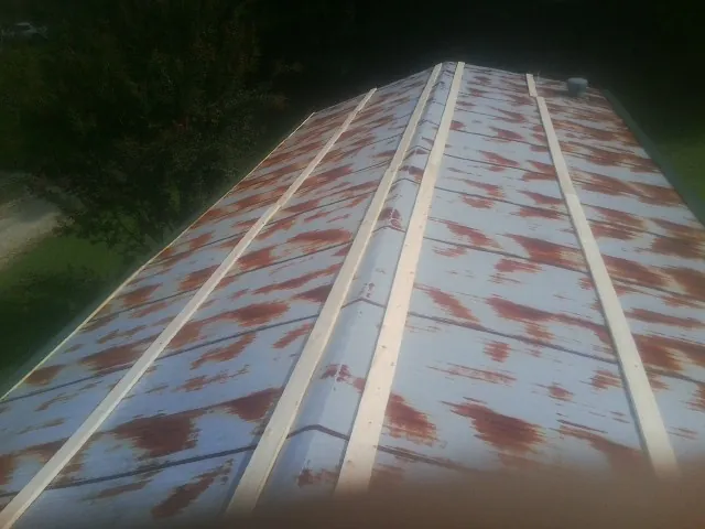 Rusted metal roof panels with new wood purlins before replacement — Storm Damage Roof Repair in Minnesota City by Roofing Brothers