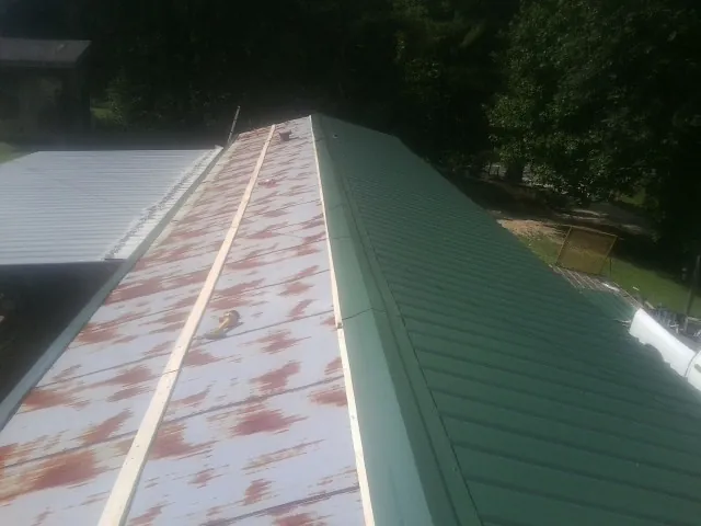 Old rusted panels beside newly installed green metal roofing — Wind Damage Roof Repair by Roofing Brothers in Minnesota City