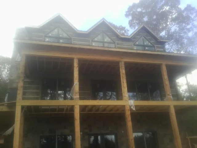 Dormers and porch framing on a large log home under construction — Roof Coating work by our crew in Minnesota City