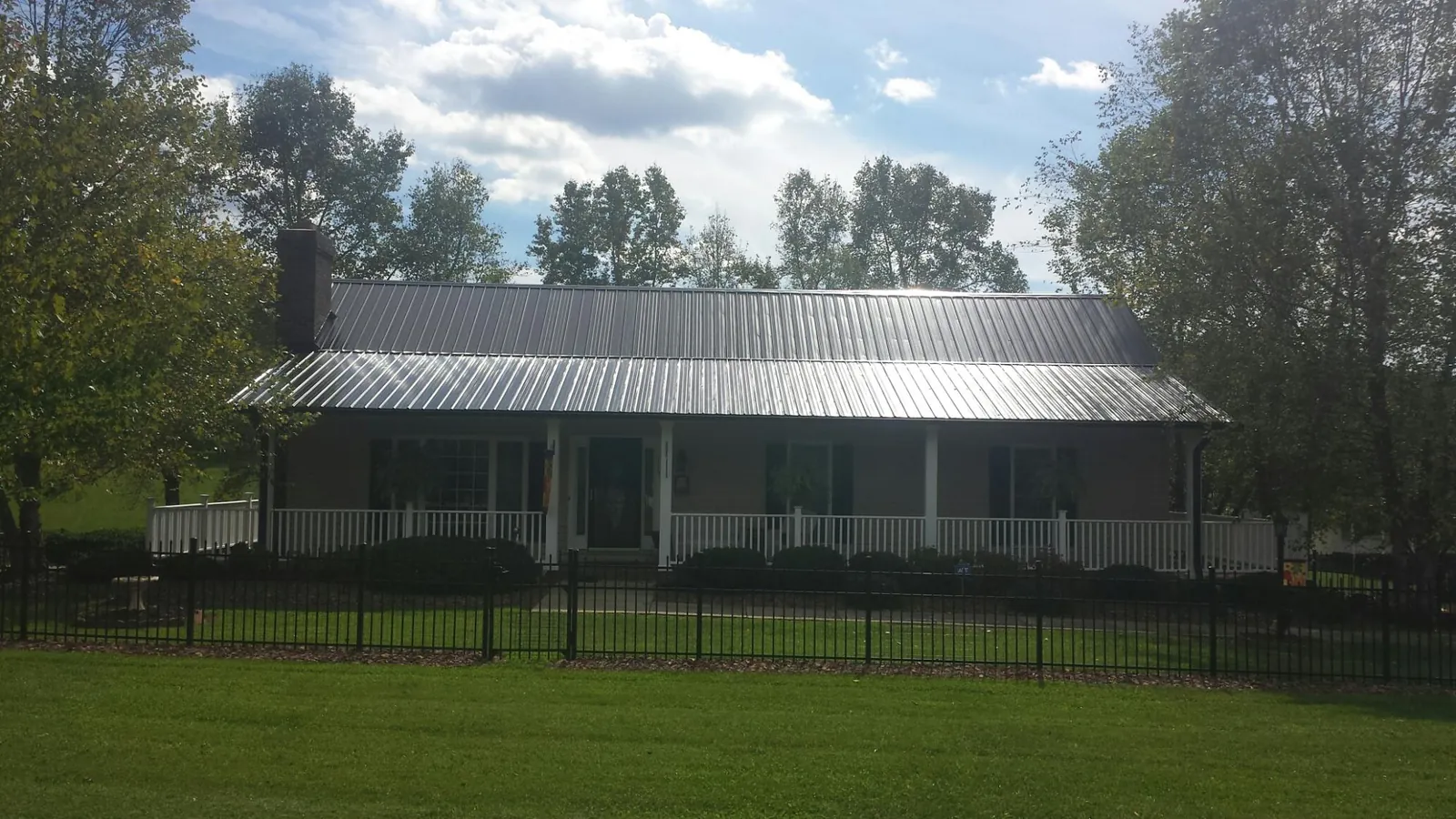 Gray metal roof on a brick ranch with a full width front porch — Gutter Guard Installation work by our crew in Minnesota City