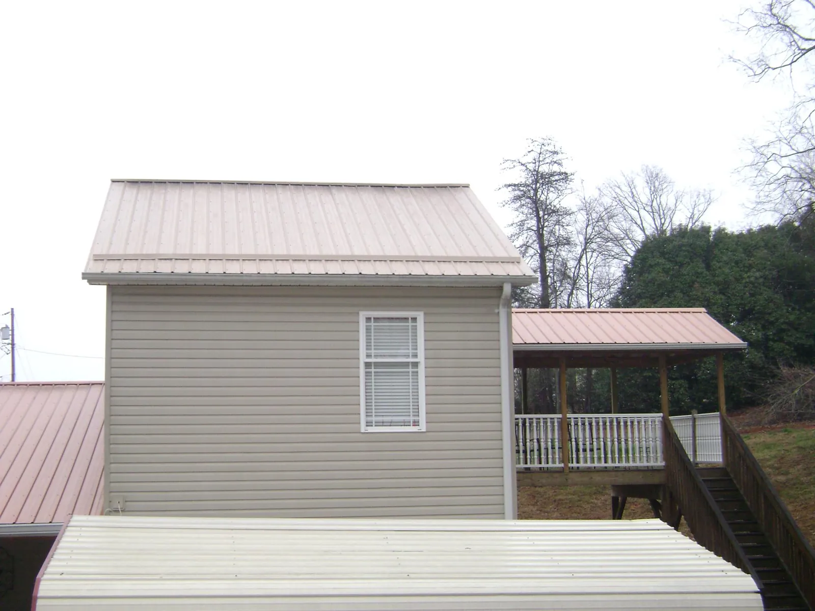 Tan metal roofs on a two story addition and attached porch in Minnesota City