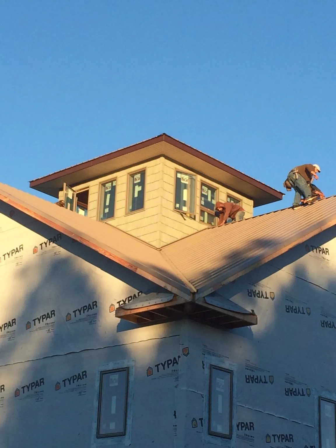 Roofers working around a rooftop cupola on a new metal roof at sunset — Roof Waterproofing in Minnesota City by Roofing Brothers